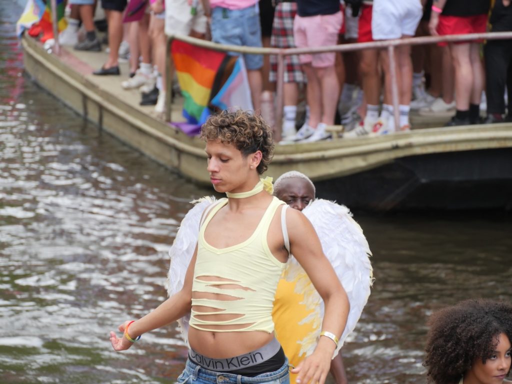 Man with angel wings dancing during the Amsterdam World Pride 2026 Canal Parade.