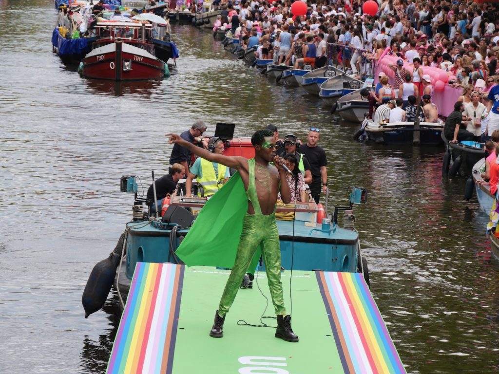 A man sings wearing a green outfit at the Amsterdam World Pride 2026 Canal Parade.
